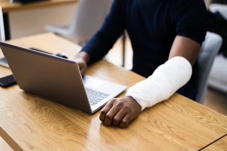 Man with arm cast on the computer